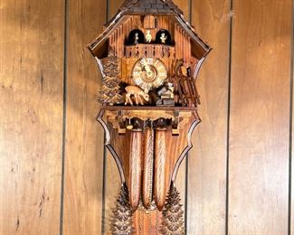 WINTER LODGE CUCKOO CLOCK  |  Edelweiss cuckoo clock featuring a winter lodge scene, with Roman numeral markers, pine tree pendulum, having a Swiss musical movement playing Lara's Theme from Dr. Zhivago, with label on verso - l. 12 x w. 6 x h. 26 in. (clock)