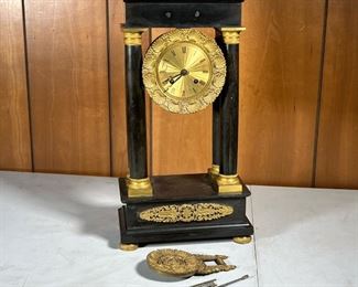 REGAL SHELF CLOCK  |  Open face shelf clock with shell motifs surrounding the engine turned clock face, Roman numeral markers, flanked by four columns over a base with gilt accents and a large flower form pendulum - l. 10 x w. 5 x h. 19 in.
