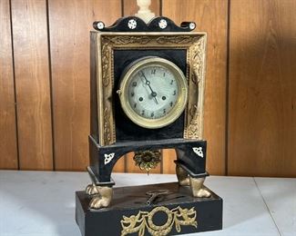 ORNATE SHELF CLOCK  |  Black and gilt shelf clock with an alabaster finial and applied accents; engine turned clock face with Arab numeral markers, on four feel over a block base, with a flower form pendulum; comes with key - l. 11 x w. 5 x h. 20 in.