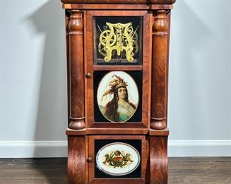 EGLOMISE WALL CLOCK  |  Nicely figured wood case marked Eight-Day Weight Clocks / Seth Thomas", having a finely painted eglomise panel of a figure in a feathered headdress above heraldry device with lions; clock missing the face - l. 18 x w. 6 x h. 32 in.