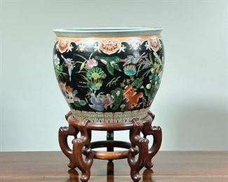 ENAMELED PORCELAIN JARDINIERE  |  Or "Fish Bowl," the outside, decorated extensively with fish, birds and insects among lilies, lotus blossoms and other flowering branches, the inside decorated with goldfish among seaweed, with mark on the bottom, on a conforming wood stand - h. 12 x dia. 15 in.