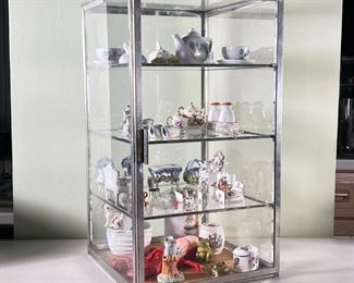 CURIO DISPLAY CASE  |  A collection of miniatures, housed in a glass display cabinet, with various porcelain items (figurines, miniature vases and tea sets, etc.), including Limoges, Basil Matthews, Grafton, etc. - l. 10 x w. 10 x h. 19 in. (glass case)
