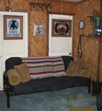Black tubular Metal Futon Sofa with Black Upholstered Cushion. Slitz Malt Liquor and Pony Express Mirrors in back ground.