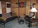 Over View of Room Area, Featuring Black Futon Sofa, Glider Rocker with Foot Stool, Lamp Table, Etc.
