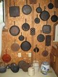A Wall of Cast Iron Skillets, Griddles, Muffin Pans, Tea Kettles and Various Crocks
