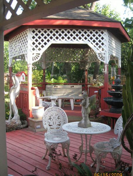 Backyard Gazebo featuring White benches and show with White  Metal Patio Table and Two Chairs.  