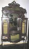 Victorian Etarge're raised on pad feet Queen Anne legs, ornately carved with applied decoration on crown. Carved scroll & lattice shelf supports. 2 glass front cabinets on each side backed with original brocade fabric. The lower cabinet has bow front There are 4 seperate decorative bevel mirrors. All appears to have original finish. The overall measurements are 92"H x 48"W x 18"D