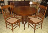 Antique Oak Empire style 48" Round table with extra 12" leaf. Table is shown wtih four Antique Spindle backed Oak Chairs with faux leather replacement seats.