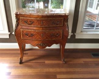 Exquisite Louis XV style commode with tulip wood and rosewood veneer finely inlaid with diamond pattern and ornamental frieze. The two “sans traverse “ drawers are decorated with fine gilt bronze mounts . The top is rose/ecru colored marble. Made in France 1860 approximately 