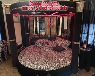 Circular bed with mirrored canopy with lights and electrical outlets. 