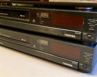 Vintage AV equipment including Toshiba VHS VCR players, Samsung DVD/VHS VCR combo player, DVD/VHS VCR combo player, Sony DVD player, Panasonic Omnivision VHS VCR player, Toshiba VHS VCR player, Radio Shack Amplified Video Selector