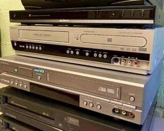 Vintage AV equipment including Toshiba VHS VCR players, Samsung DVD/VHS VCR combo player, DVD/VHS VCR combo player, Sony DVD player, Panasonic Omnivision VHS VCR player, Toshiba VHS VCR player, Radio Shack Amplified Video Selector