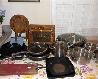 Vintage bread box, vintage Wear Ever knife set, and Cuisinart and Kitchen Essentials pan sets.