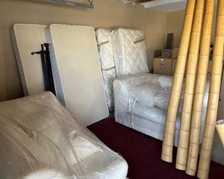 Twin beds, white sofa pieces, large bamboo poles