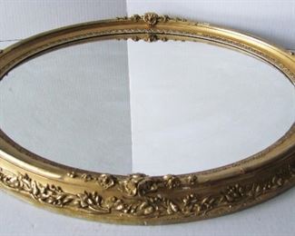 Lot 2   C/1870 Gilt oval Mirror, wood plank backed, raised floral decorations, 25" x 29" overall.  Condition:  Original mirror has some minor streaks, some small touch-ups to the gilt, edges have minor wear.  