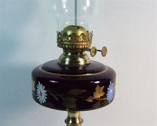 Lot 22   C/1880 Ruby Glass Oil Lamp w/black glass base, hand painted floral decorations, 20" h.  Condition:  No damage found.    