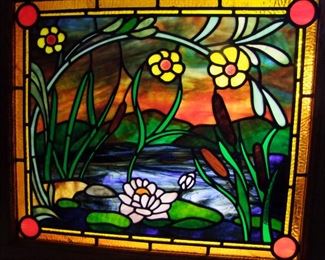 Lot 31   Dated 1982 Hand leaded stained glass window, Setting Sun over a Pond w/Lily pads and Cat tails, "K.R. Kidd 3/82" etched into the glass, 24" x 20 1/2" h. in a heavy oak milled frame 28 1/2 x 25" h., includes brass hanging chain.  Condition:  No damage found. 