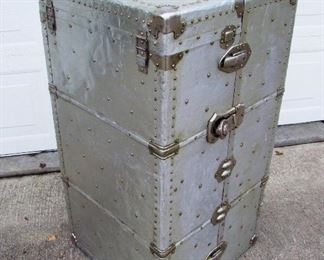 Lot 64   Dated 1930 all Aluminum Aircraft Steamer Trunk, marked "Long Manufacturing Co.", riveted construction, cloth covered interior including 3 drawers, "Tilt" drawer for shoes and 7 wood hangers plus a locking drawer bar, 21" sq. x 41" tall. Condition:  Various scratches and light dents from use, overall good condition, missing handle on top, no key.     Note: When long distance air travel began after WW2, Passengers were limited to specific weight amounts for luggage. The lighter the luggage, the more you could take on your trip!