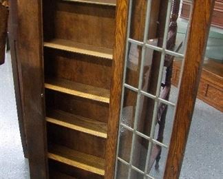 Lot 36A  C/1910 Mission Oak style Bookcase. Single leaded door, 5 shelves. 24"w. X 7"d. X 56"h.  Condition: Refinished.     Est. $100 - 200