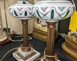 Early 20th century Bohemian white opaline glass overlay cut to emerald green. The lamps are cut in geometric and leafy patterns and the white has a dainty floral motif.  Bronze and marble  bases