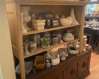 Mid century cabinet on bottom has large metal lion head hardware.  Top cabinet is a simple beige display piece perfect for showing off your collection. Also pictured is a collection of Pottery and Vintage planters.