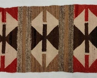 NAVAJO HAND MADE WOOL SMALL RUG. 36 X 17". TWO HOLES ON ONE END. SLIGHT COLOR RUN ONTO THE NATURAL AREAS. RED AREAS ARE SLIGHTLY MORE MAUVE THAN PHOTOS DEPICT