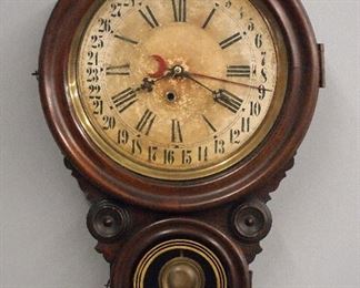 A turn of the century Ingraham Meridian model wall clock, made for the Lovell Manufacturing Co., Limited, of Erie, PA.  8-day time only movement with simple calendar.  Grain painted "Rosewood" case with two molded doors.  Wear, dial damage and discoloration, running when cataloged.  24" high.  ESTIMATE $200-300