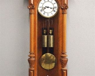 A late 19th century 2 weight Vienna regulator wall clock.  8-day weight driven time and strike movement with two part porcelain dial and Roman numerals.  Walnut case with shaped crest and molded cornice over a long door with turned pilasters and shaped lower drop.  Older finish with some wear, replaced crest and weights, running when cataloged.  47 3/4" high overall.  ESTIMATE $200-300
