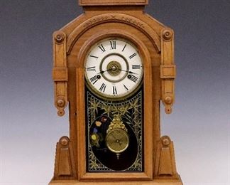 A late 19th century New Haven "Maas" model kitchen shelf clock with artist's palette glass.  8-day time strike and alarm movement with a papered metal dial and Roman numerals.  Walnut case with carved detail, shaped crest over an arched door and molded base.  Paper label 80% intact.  Older refinishing with minor wear, re-papered dial, running when cataloged.  23" high.  ESTIMATE $400-600
