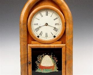 A 19th century William L. Gilbert "Beehive" model shelf clock.  8-day time and strike movement with a painted metal dial and Roman numerals.  Mahogany case with arched top over a single door with clear dial glass and reverse painted Beehive lower on a simple squared base.  Paper label 80% intact.  Old finish with minor damage, small veneer repairs, some dial wear, running when cataloged.  18 3/4" high.  ESTIMATE $300-500
