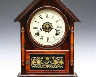 A 19th century Waterbury "Dexter" model shelf clock.  8-day time, strike and alarm movement with a painted metal dial and Roman numerals.  Rosewood case with a molded pediment crest over a single door with painted lower glass flanked by applied pilasters on a molded base.  Paper label 80% intact.  Older refinishing with minor wear, running when cataloged.  17 " high.  ESTIMATE $100-200
