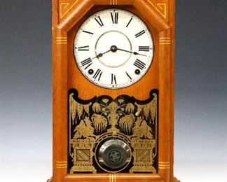 A late 19th century Seth Thomas "Omaha" model shelf clock from the "City Clock Series".  8-day Lyre shaped time and strike movement with a papered metal dial and Roman numerals.  Oak case with Gilded detail and spindle gallery over a single long door with stenciled glass on a molded base.  Paper label 80% intact.  Original finish with minor wear, running when cataloged.  19" high.  ESTIMATE $300-500
