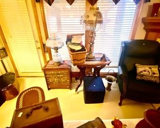 vintage table, green leather wing back chair, foot stool, brass items by fireplace, beautiful lamps basket of gloves