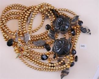 Caroline necklace with 5 strands of oval, golden colored, fresh water pearls. Carved black onyx/agate flower, gold tone butterfly with red, green and blue stones.