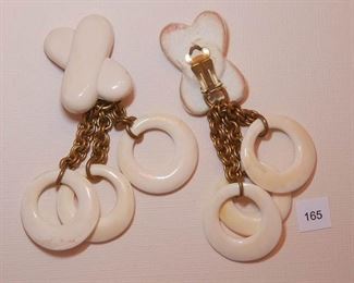 Ben-Amun Clip back Silver Tone. Each Drop earring measures approx. 3 3/4” in length. Top portion is Faux ivory in an “X” form. Attached is a triple, double link chain, gold tone in 3 different lengths. Attached to the chain is a faux ivory piece with an off-center hol. Each piece measures approx. 1 3/16” in diameter.