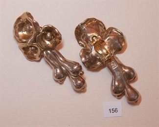 Clip back Silvertone. Each rigid electro firm earring measures approx. 2 7/8” in length.  Three round form flowers are at the top and 3 long pod like sections are below.