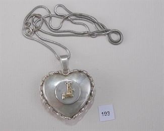 Jo Dell 925 - Sterling Silver. The SS puffed heart pendant measures approx. 1 5/8” in width. A round flat disc, 19mm in diameter, is attached to the front with a gold tone figure. Around the edge of the heart is attached a link chain. The flat “V” bail holds SS snake chain measuring approximately 24 3/4” in length with a spring ring clasp.