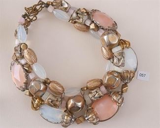 Arthur Koby. Gold Tone 3 strand necklace measures approximately 15” in length (the shortest) and approximately 18 1/2” (the longest). A mixture of shapes, sizes and textures with light blue and pink faceted and smooth stones.