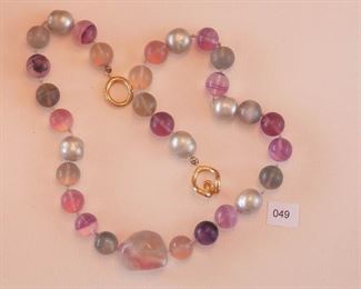 Ciner gold Tone clasp. The single strand necklace measures approximately 19 3/4” in length. Twenty-four round polished beads, fluorite, measures approximately 12mm in diameter.  Just off center is one chunky, polished fluorite, measuring approximately 24 mm in length. Also there are 6 out-of-round grey faux pearls each measures approximately 12mm in diameter.