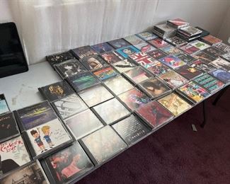 Many  great rock CDs many of the artists include kiss Jackyl, Pink Floyd, Peter Frampton, Deep Purple, The Black Crowes, Boston, Led Zeppelin, Alice In Chains, two live crew, The Jerky Boys, Jimi Hendrix, Metallica, Jethro Tull, Pearl Jam, Guns N’ Roses, Whitesnake, White Lion, Journey, slaughter, beastie boys, and many many more. The cities in the picture are double triple and multiple stacked.