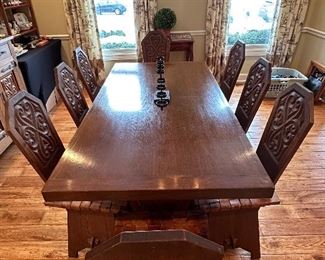 This dining set was purchased in the early 1950s by our homeowner's in-laws. It was hand carved in Brittany, France by master carpenters.  Truly unique and a show-stopper!  The seats are woven in leather! 
