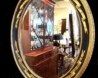 3i1. One of a pair of matching oval black gilt mirrors
