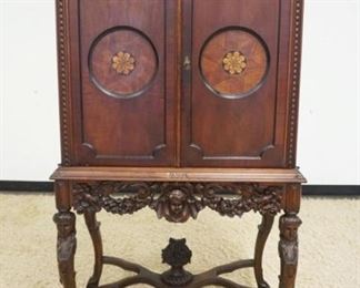 1153	OUTSTANDING WALNUT CARVED 2 DOOR CABINET, DOORS HAS 2 ROUND INLAID PANELS, INTERIOR W/3 SHELVES & ONE DRAWER, BASE HAS CARVING OF WOMAN BUST ON ALL FOUR LEGS ALONG W/A CHERUB & FLOWER BASKET AT CENTER OF STRETCHER & PIERCED CARVING, APPROXIMATELY 35 IN X 20 IN X 63 IN HIGH
