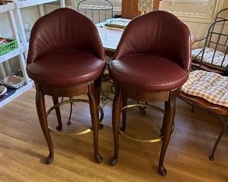 Two leather, swivel high back bar stools with brass foot rests