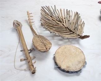 Group of Musical Instruments with Leaf Form Basket. Basket 4” tall, 24” long, 16” across, Length of each 22” and  21” long, tambourine is 8 1/2” diameter.  These instruments were gifts to my client from the Hadza, or Hadzabe, who are a Tanzanian indigenous ethnic group mostly based in southwest Karatu District of Arusha Region. They live around Lake Eyasi in the central Rift Valley and in the neighboring Serengeti Plateau.