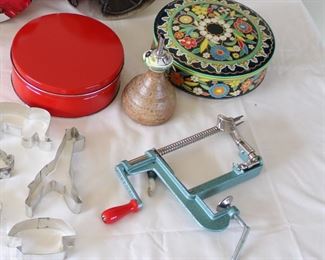Group of Kitchen Items including six round tins, one square tin, four USA Pottery custard cups, studio pottery olive oil cruet, apple corer/peeler, and eight cookie cutters, vintage green handled 3 1/4” across.