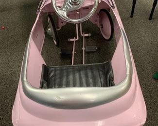 Pink pedal car for children.