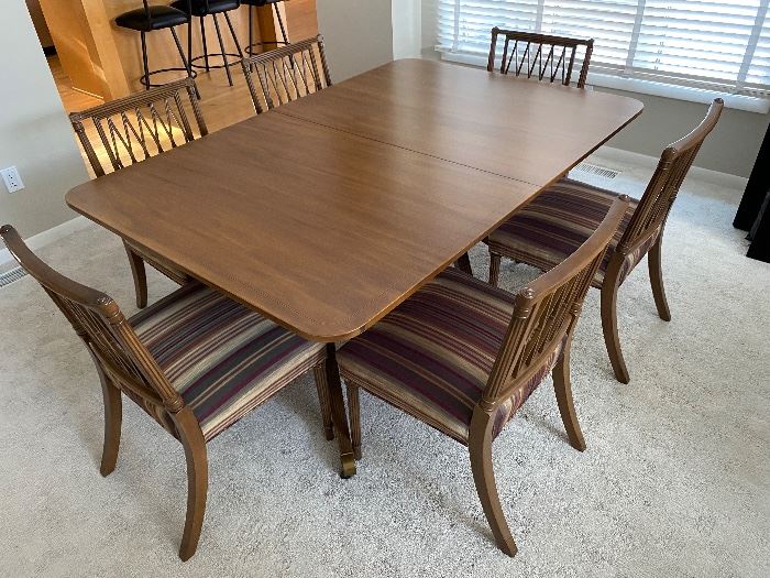 Baker dining table with six chairs, additional leaves, and pads.