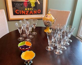 Crate & Barrel water and wine glasses, porcelain urn, 36" round pedestal table and frame Asti Cinzano print
