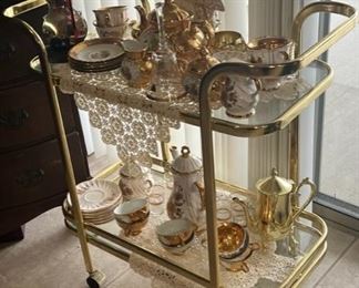 ROLLING BRASS AND GLASS BAR CART WITH PORCELAIN TEA SERVICES
